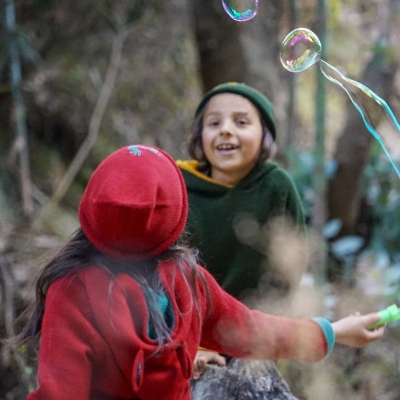 Kids playing with soap bubbles wearing baby alpaca clothes