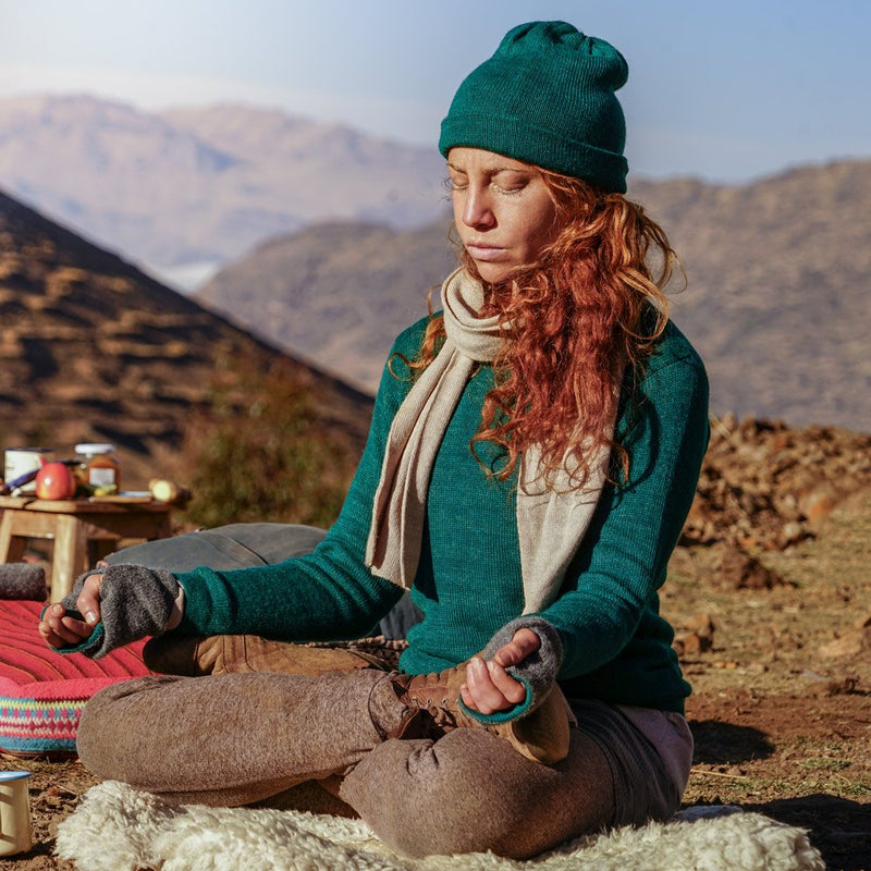 Woman doing yoga with emerald colored baby alpaca sweater, beanie, scarf and gloves