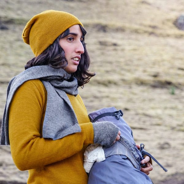 Woman holding a backpack wearing mustard colored baby alpaca wool clothes