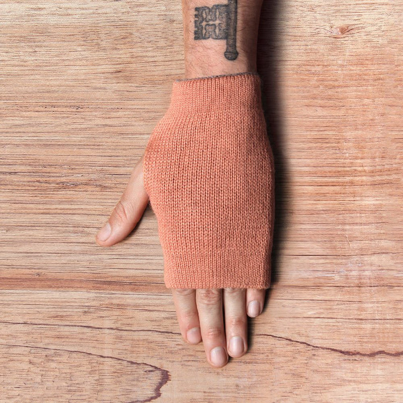 Hand with inside out gloves made of alpaca wool in the color coral