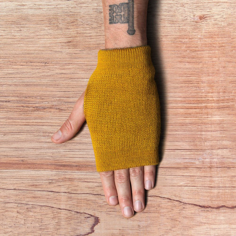 Hand with inside out gloves made of alpaca wool in the color mustard