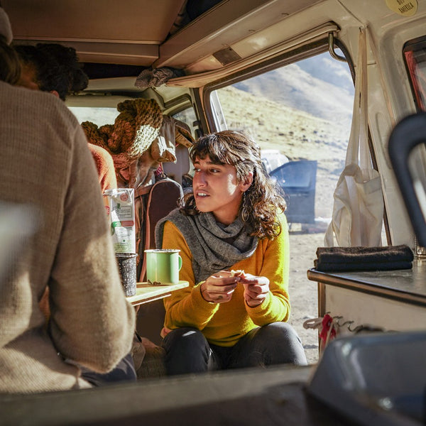 Woman sitting in a camper and wearing mustard colored baby alpaca wool clothes